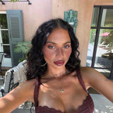 Woman wearing a brown crochet top outdoors with a building and plants in the background