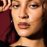 Close-up of a woman wearing a gold necklace with a pendant.