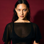 Woman wearing a black sheer top against a red background