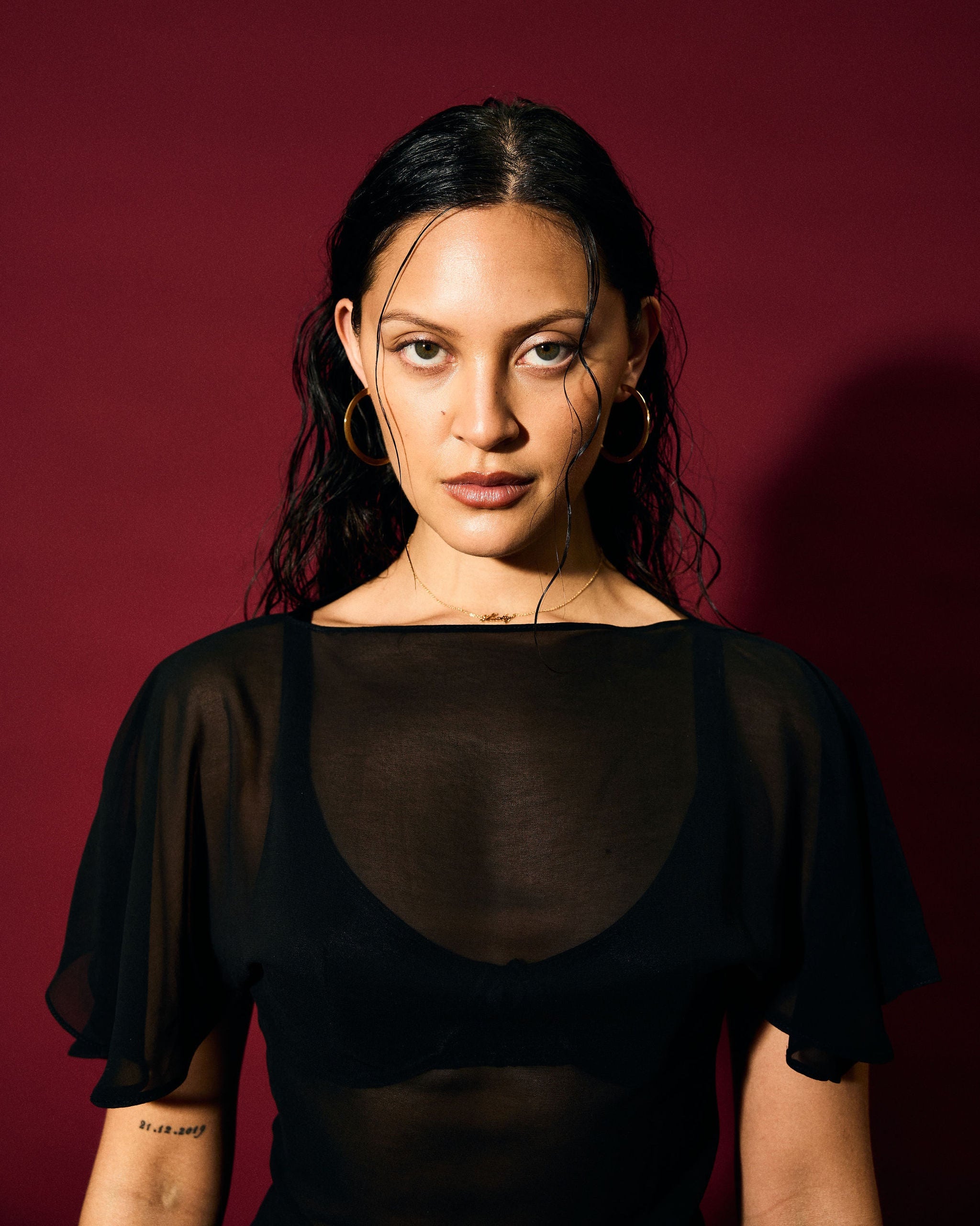 Woman wearing a black sheer top against a red background