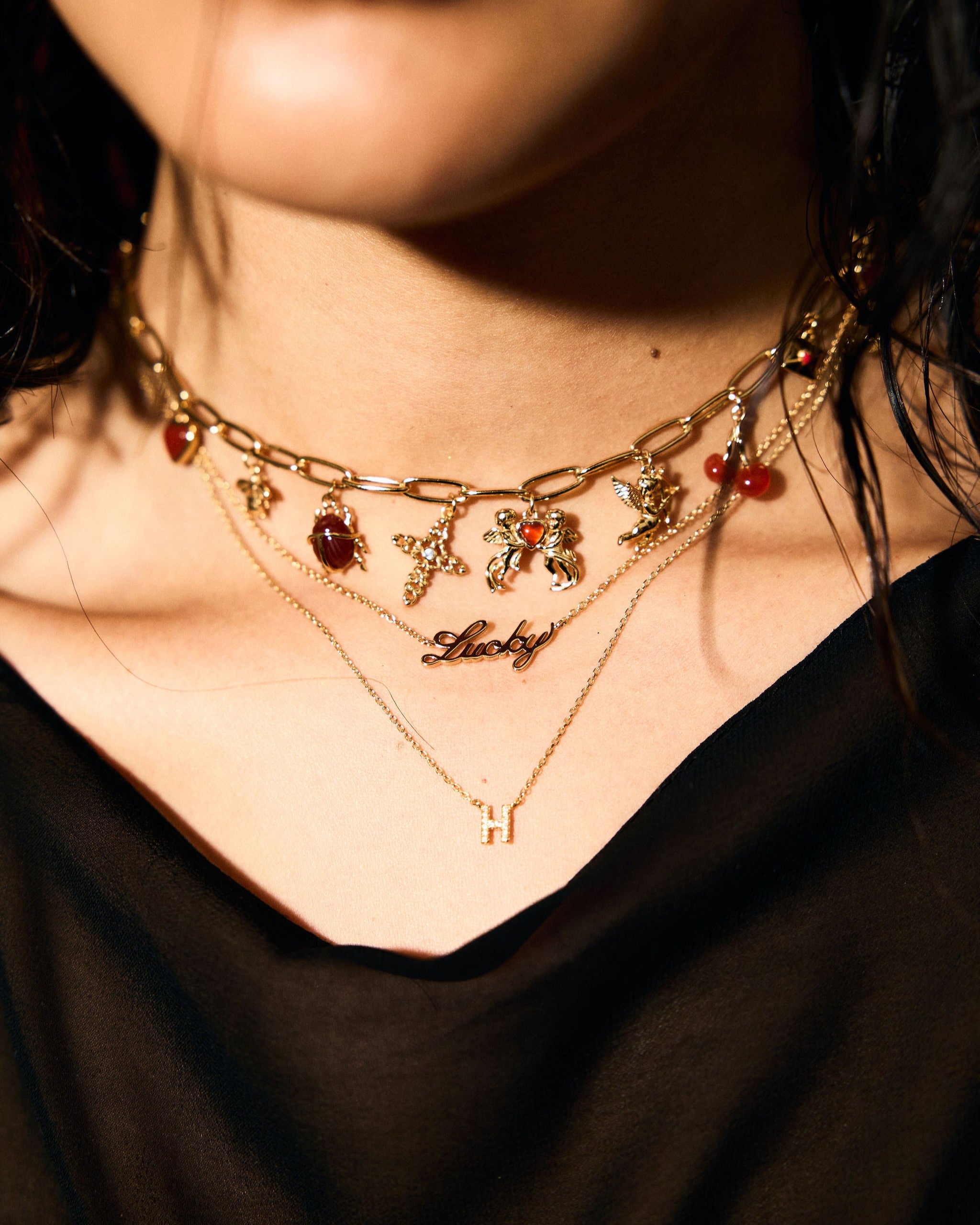 Close-up of a person wearing multiple gold necklaces with starfish and 'Lucky' pendant.