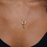 Gold necklace with a Leo pendant on a person wearing a black top.