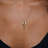 Gold necklace with a Leo pendant on a person wearing a black top.
