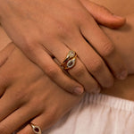 Close-up of a person's hands resting on their lap, showcasing three gold rings with marquise-cut gemstones in different settings.
