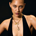 Woman wearing a black top and gold jewelry against a black background