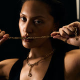 Woman wearing a gold necklace against a dark background