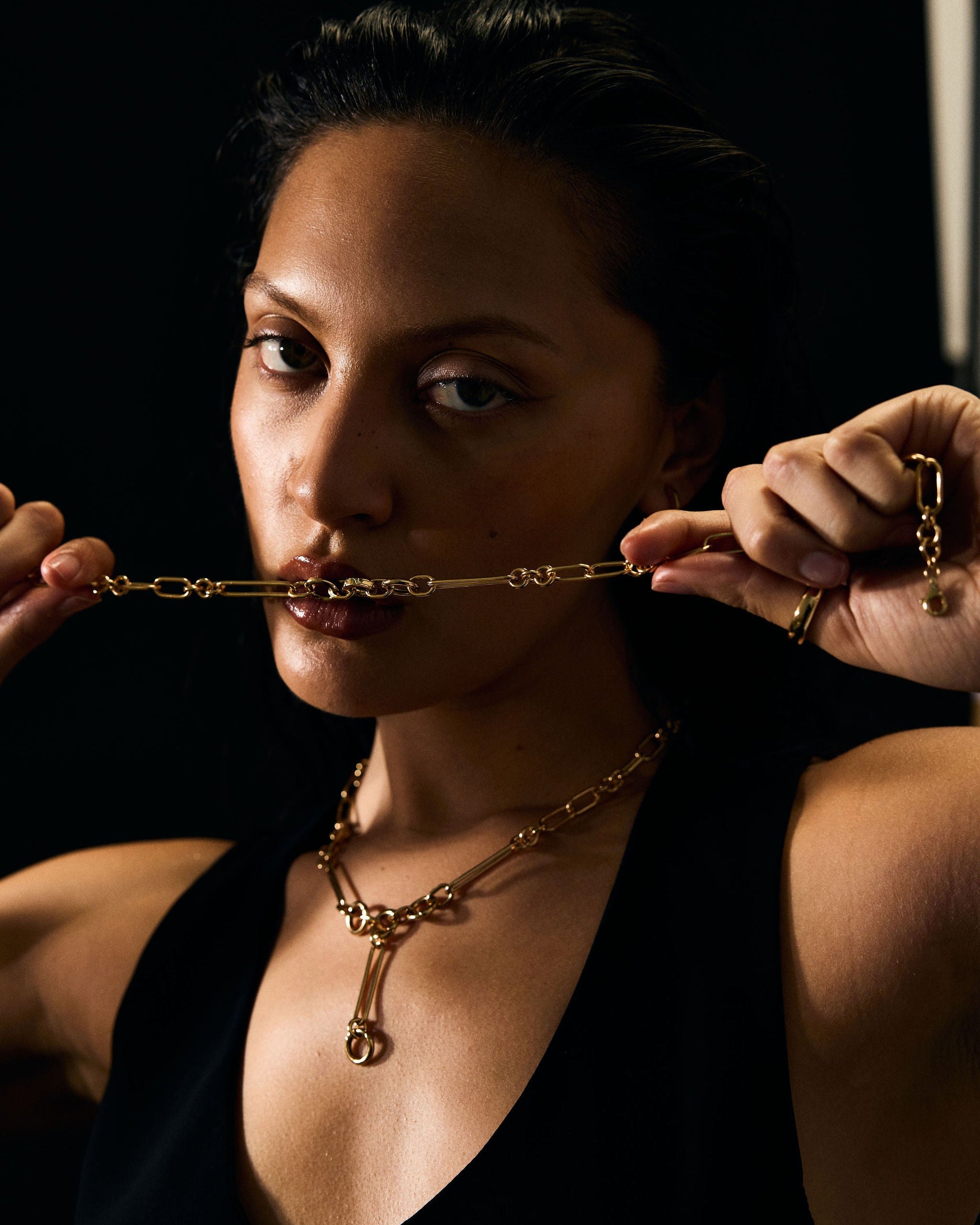Woman wearing a gold necklace against a dark background
