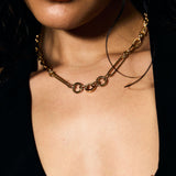 Close-up of a person wearing a gold necklace with a blurred background