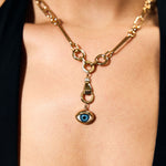 Gold necklace with an eye-shaped pendant on a person wearing a black top.