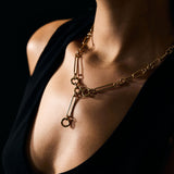 Close-up of a person wearing a gold necklace against a dark background