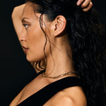 Woman with dark hair and a black top against a dark background