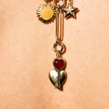 Gold necklace with heart and star charms on a beige background