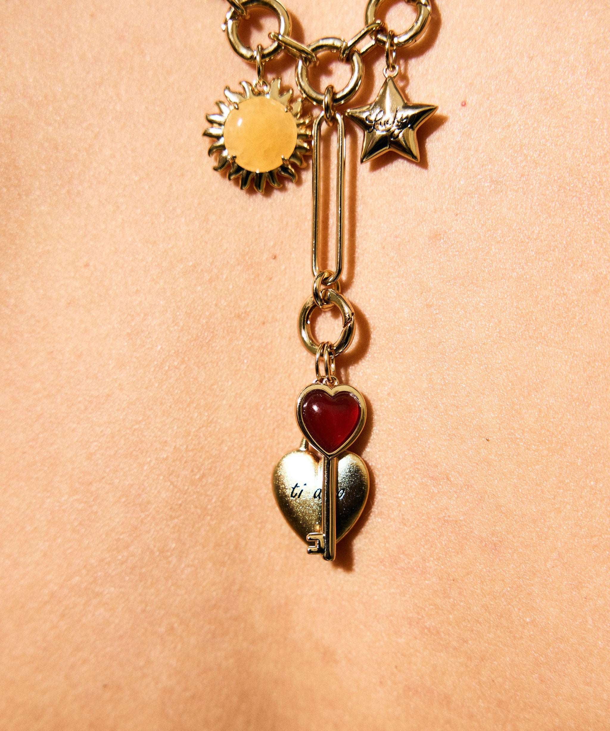 Gold necklace with heart and star charms on a beige background