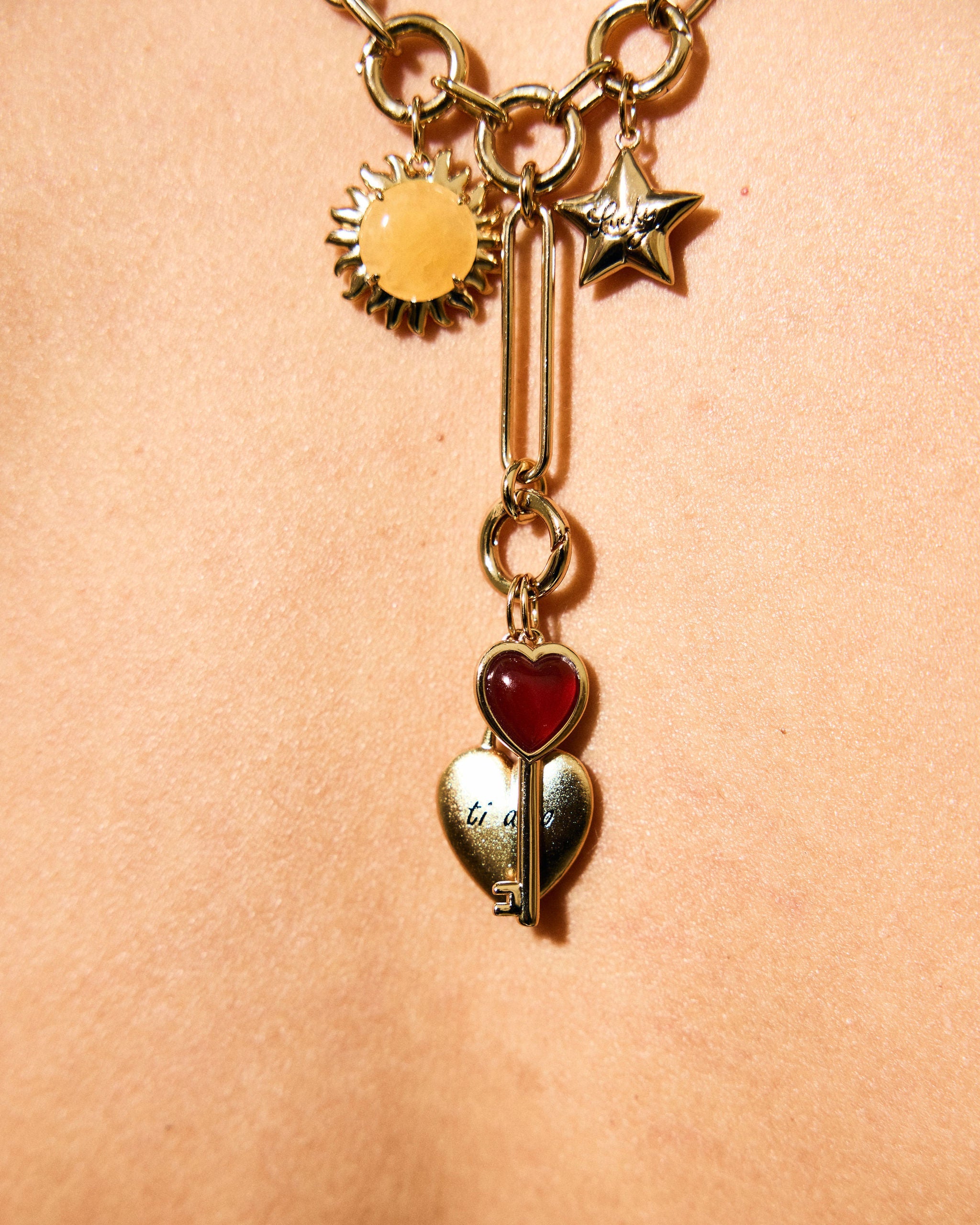 Gold necklace with heart and star charms on a beige background