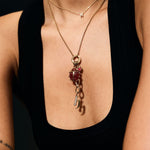 Person wearing a gold necklace with a pendant on a black background
