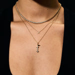 Close-up of a person wearing gold necklaces with a cross pendant on a black background