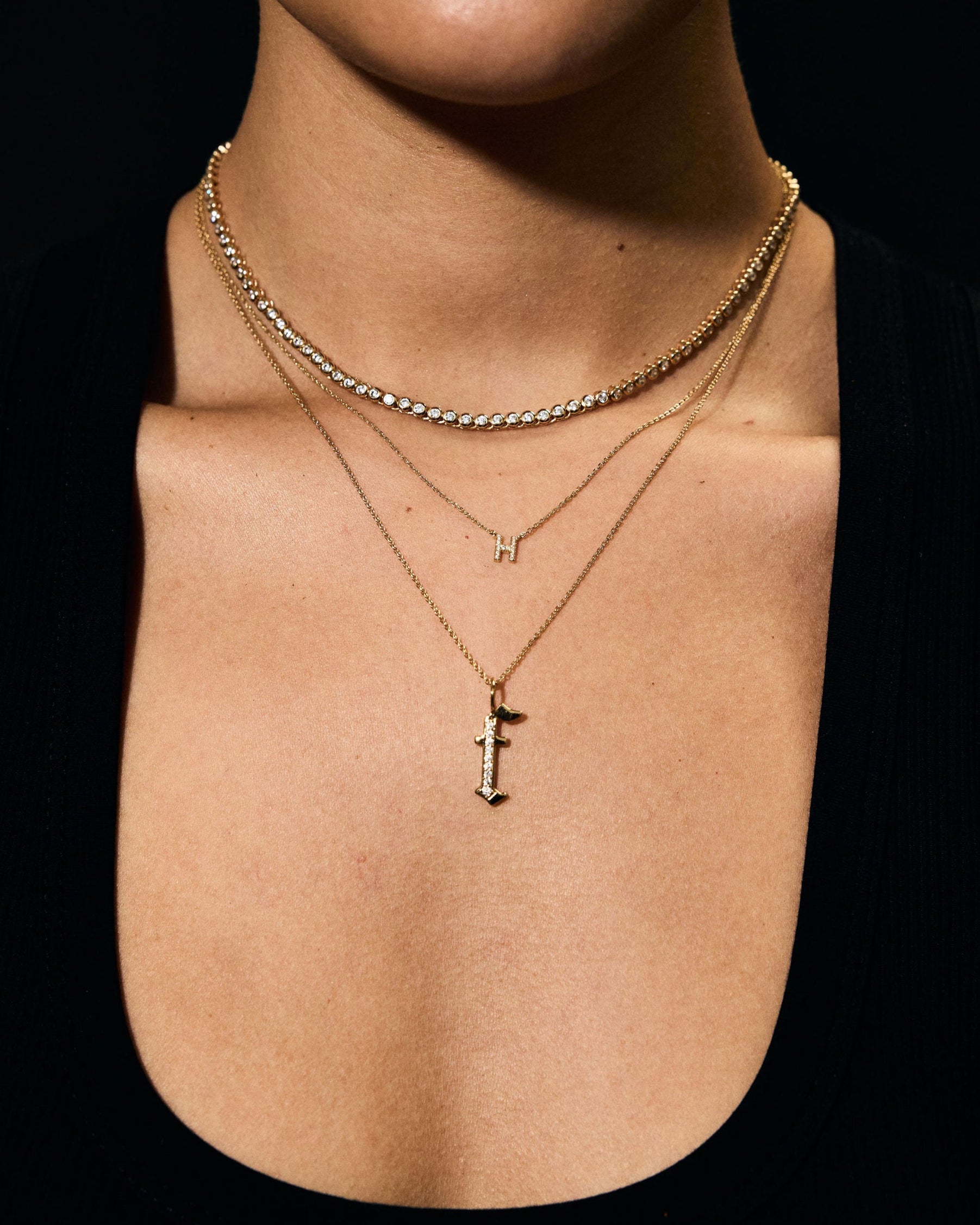 Close-up of a person wearing gold necklaces with a cross pendant on a black background