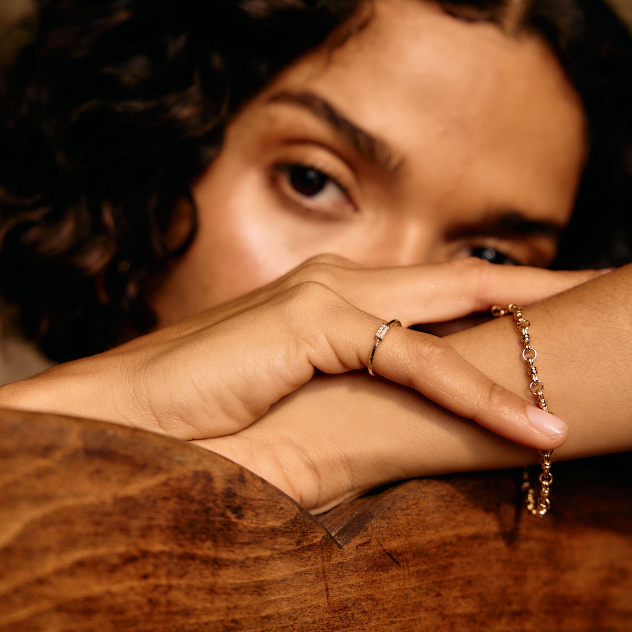 Person with braided hair and a bracelet resting on a wooden surface
