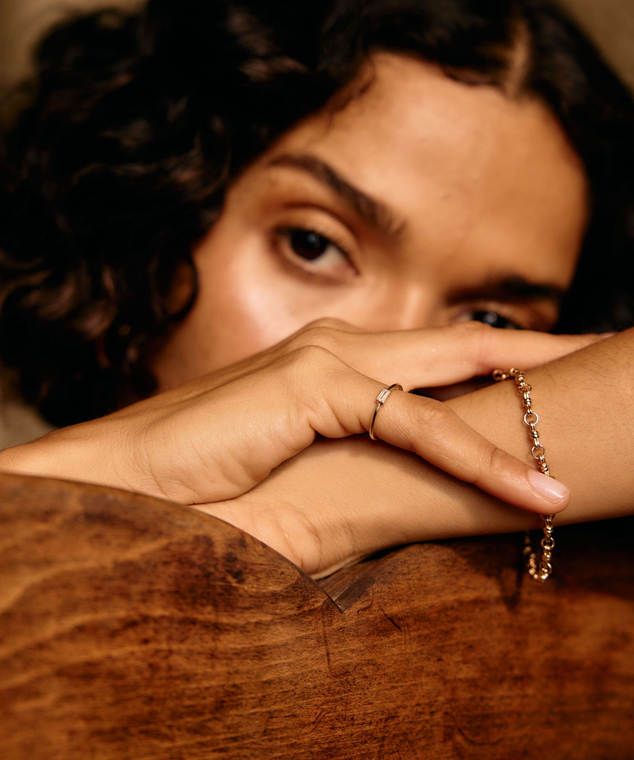Person with braided hair and a bracelet resting on a wooden surface
