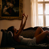 Woman lying on a couch with a painting and window in the background