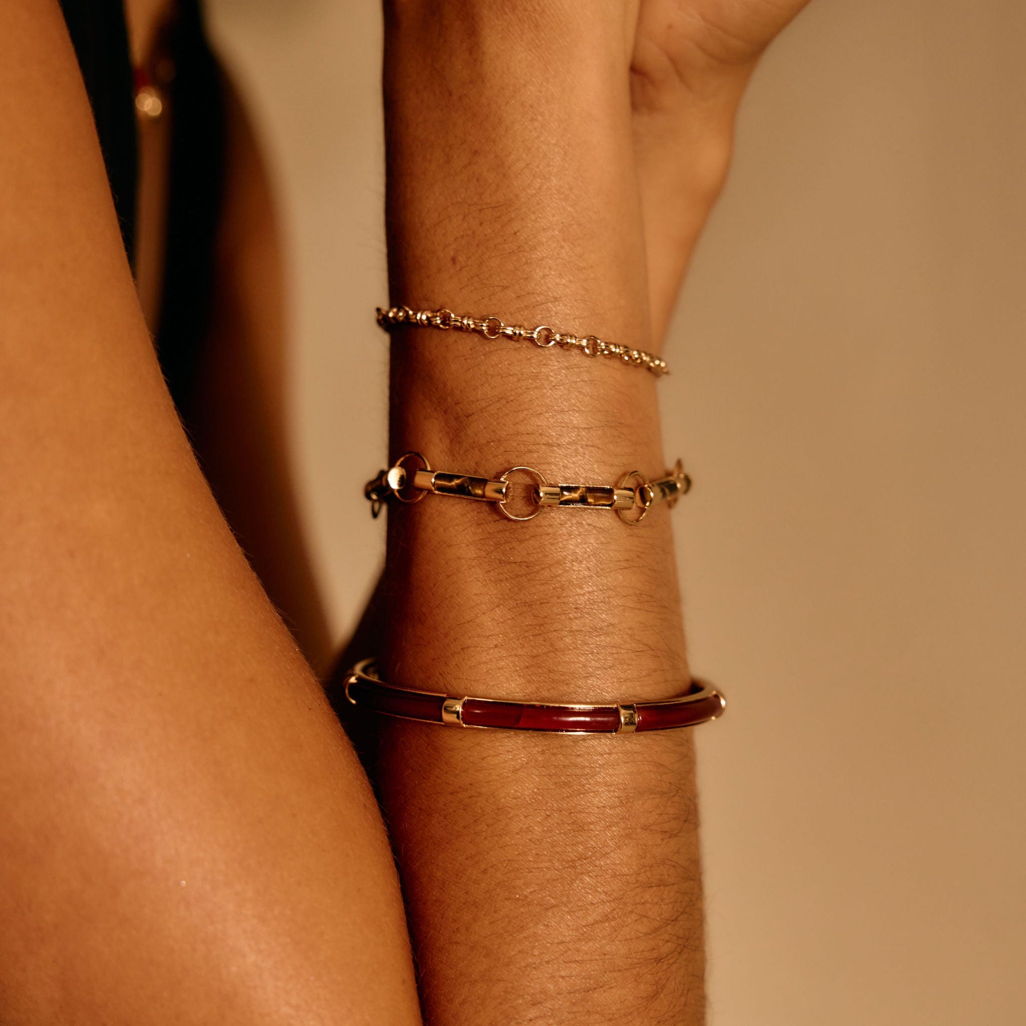Close-up of a wrist wearing multiple bracelets on a neutral background