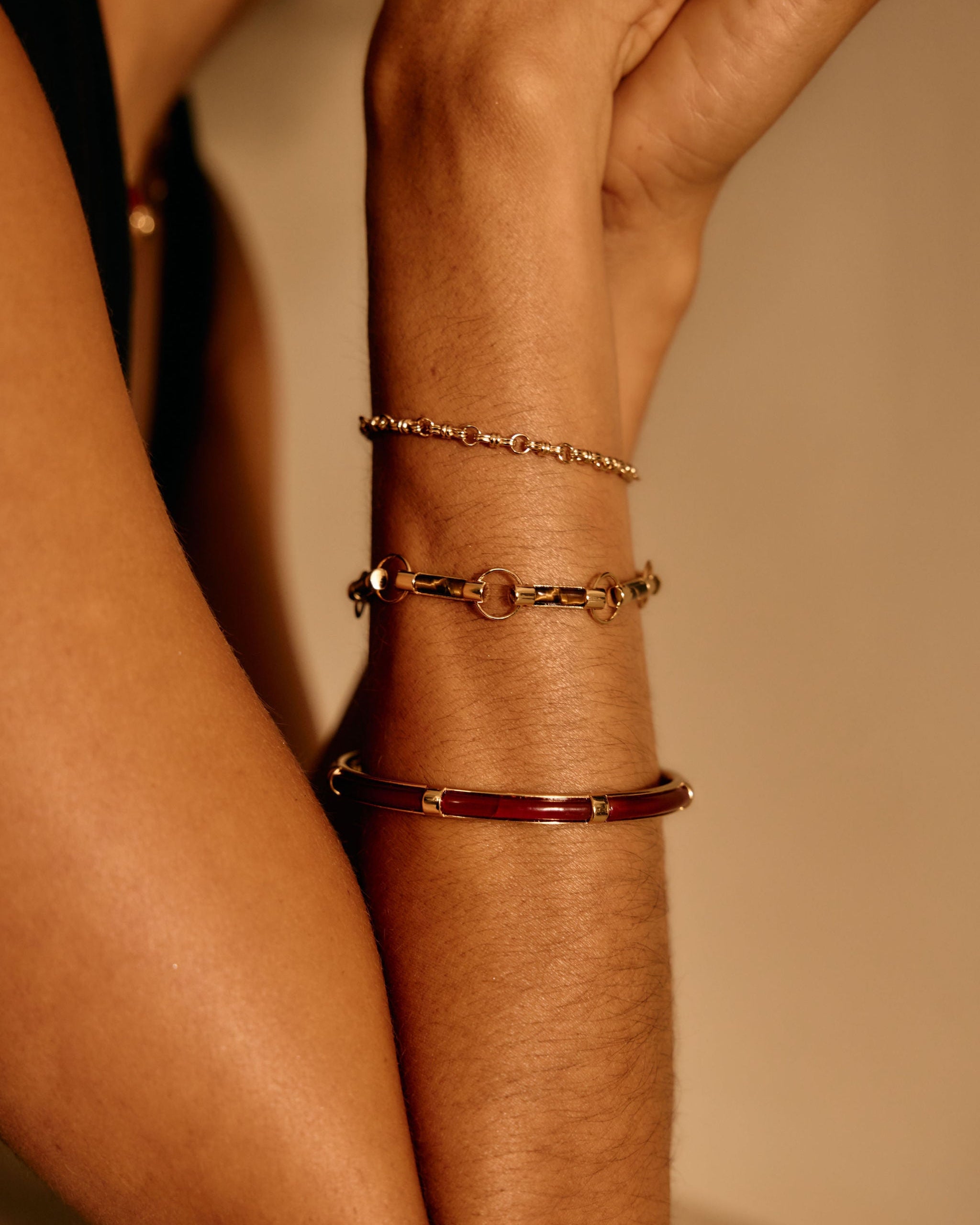 Close-up of a wrist wearing multiple bracelets on a neutral background