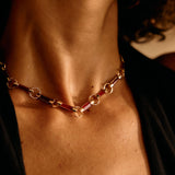 Close-up of a person wearing a gold chain necklace with a blurred background