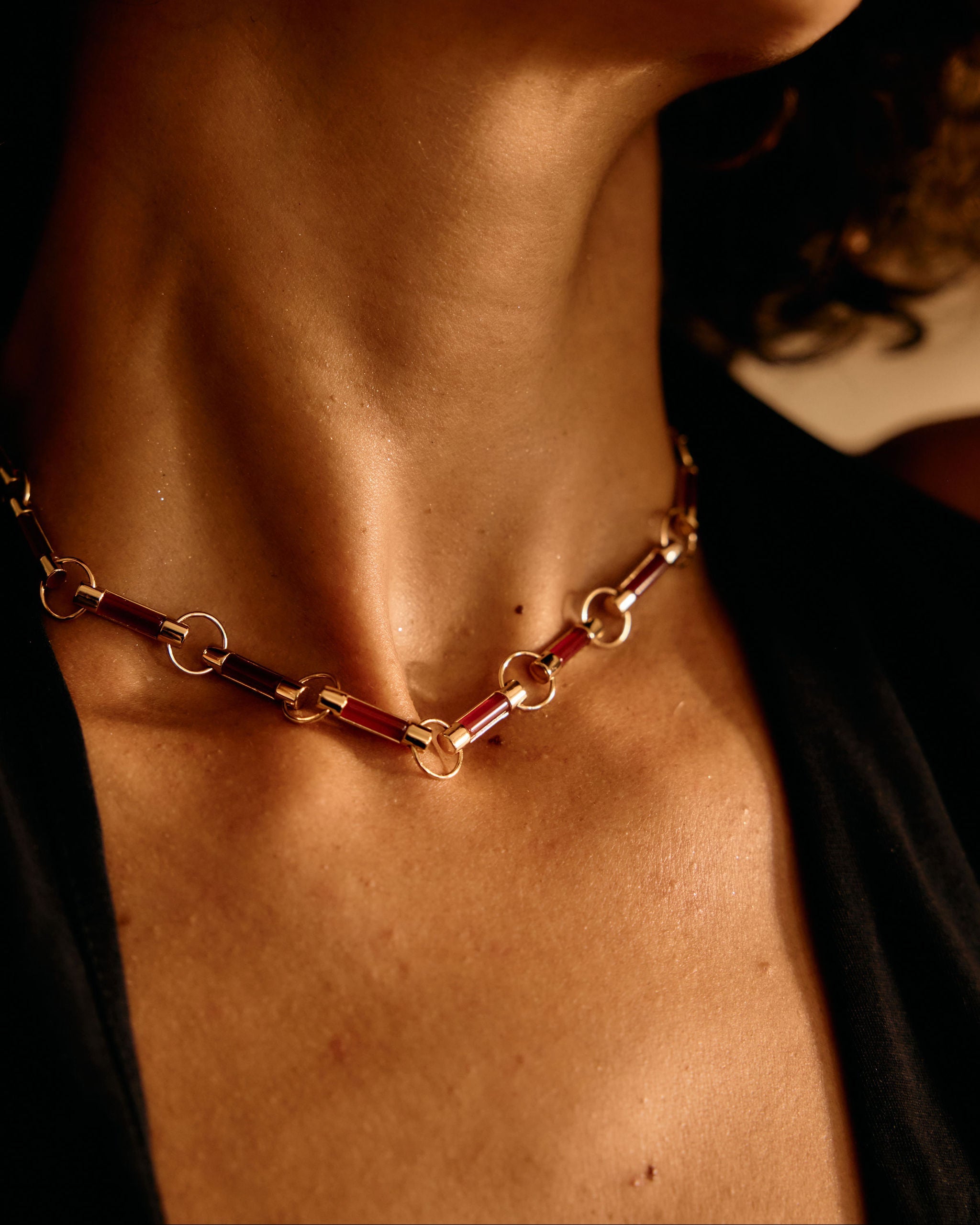 Close-up of a person wearing a gold chain necklace with a blurred background