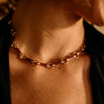 Close-up of a person wearing a gold chain necklace with a warm, brownish tint.