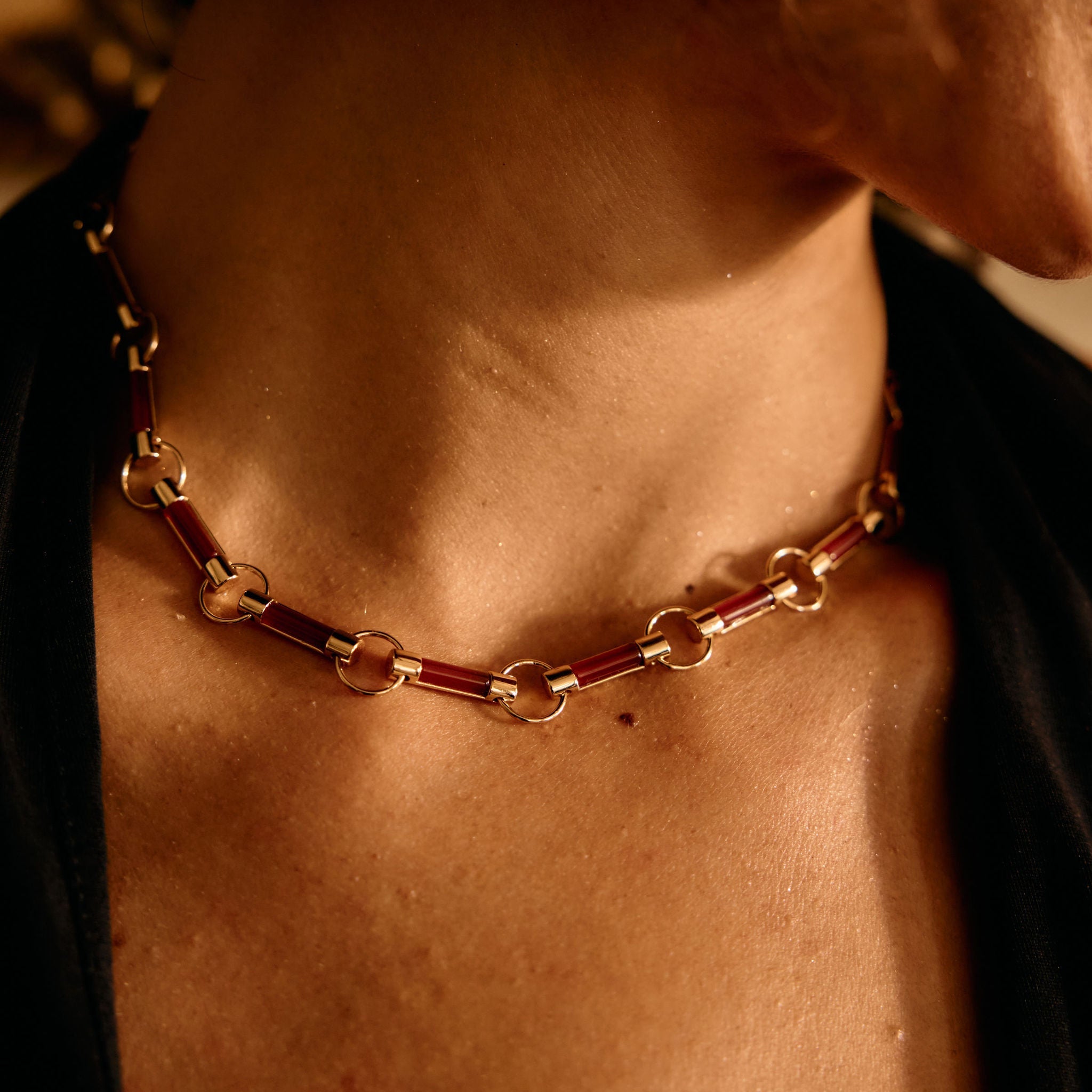 Close-up of a person wearing a gold chain necklace with a warm, brownish tint.
