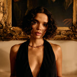 Woman in a black dress standing in front of an ornate painting