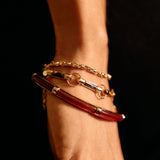 Close-up of a wrist wearing two bracelets on a dark background