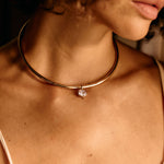 Close-up of a person wearing a gold necklace with a pendant.