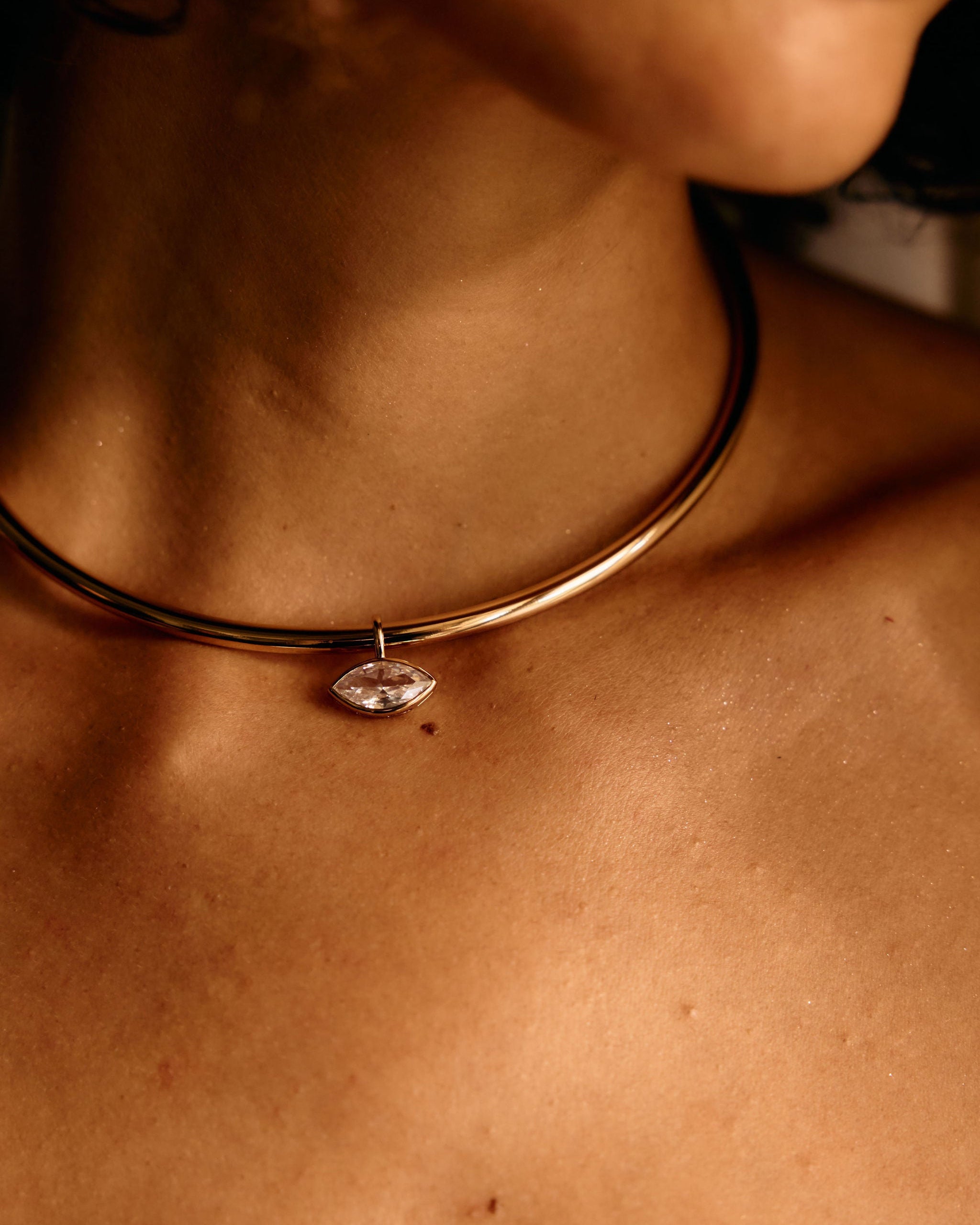 Necklace with a pendant worn by a person, close-up on skin.