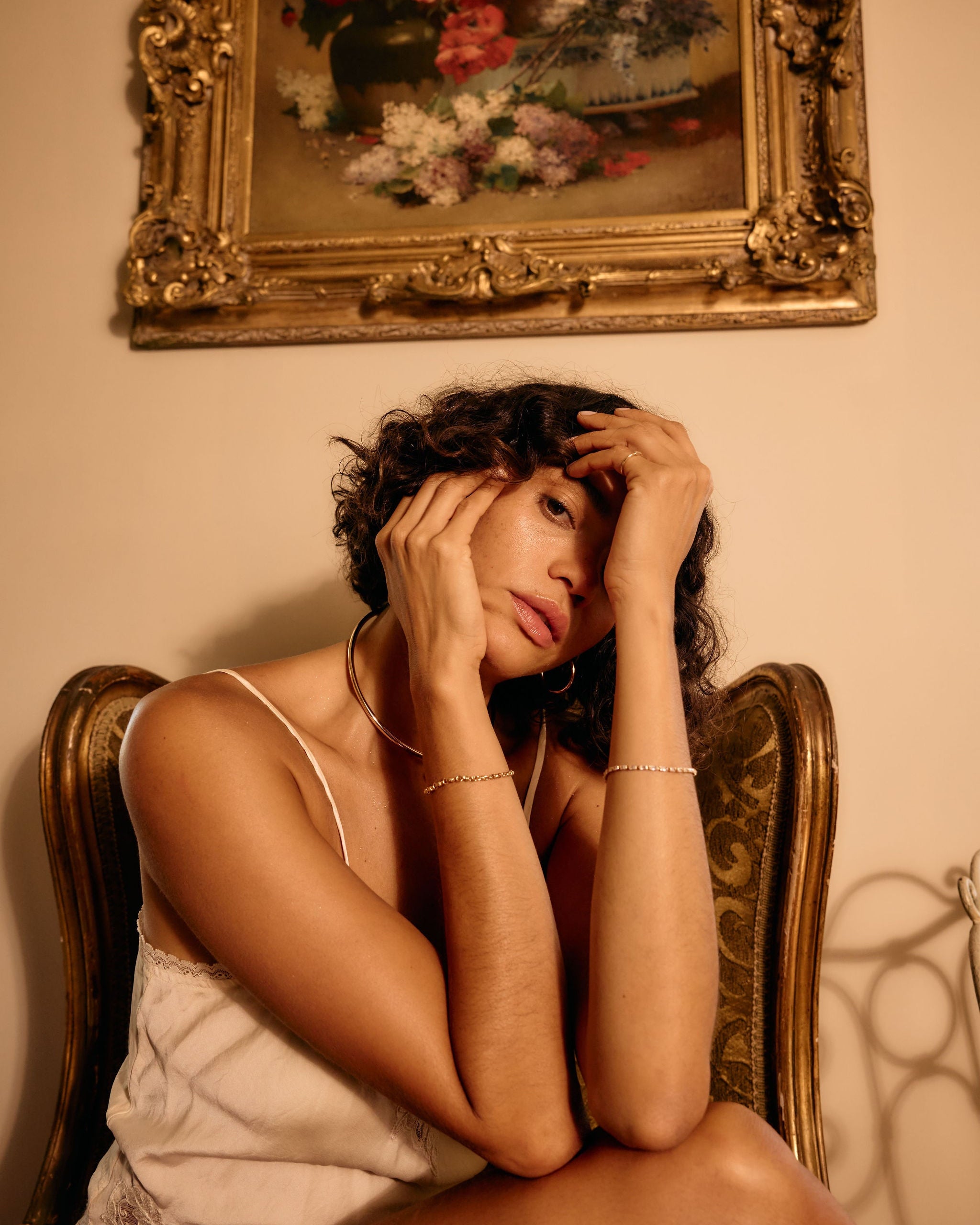 Woman sitting on a chair with a painting of flowers on the wall behind her
