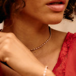 Close-up of a person wearing a red top and gold necklace with a blurred background