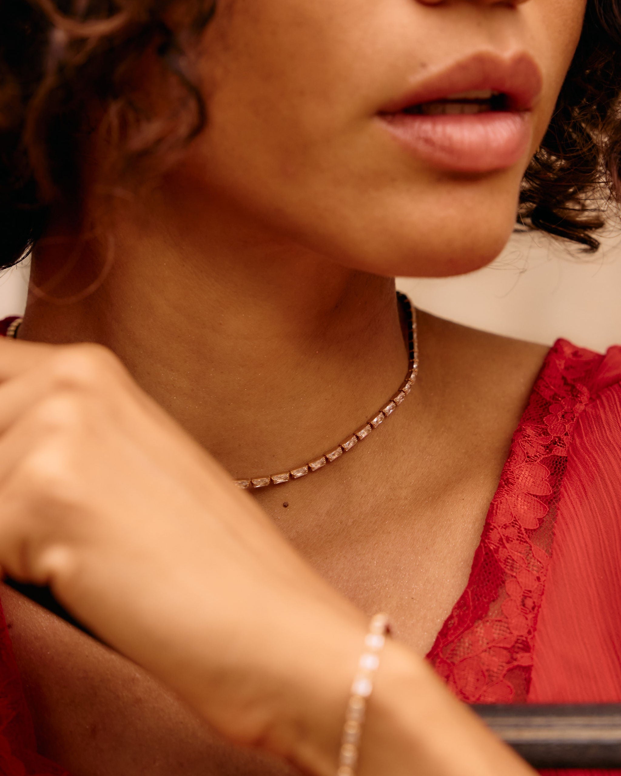 Close-up of a person wearing a red top and gold necklace with a blurred background