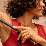 Woman in a red dress holding onto a black railing with a blurred background