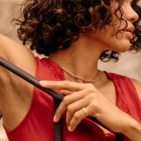 Woman in a red dress holding onto a black railing with a blurred background