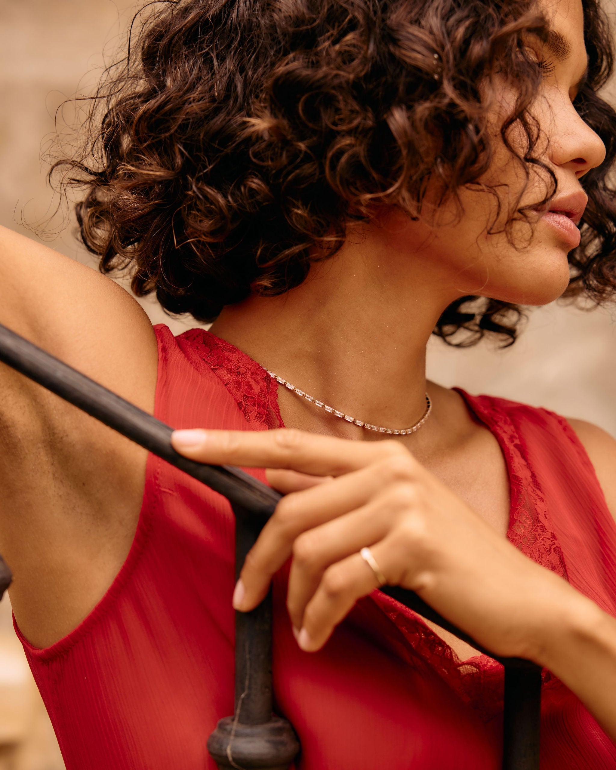 Woman in a red dress holding onto a black railing with a blurred background