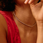 Person wearing a red top and pearl necklace with a blurred background