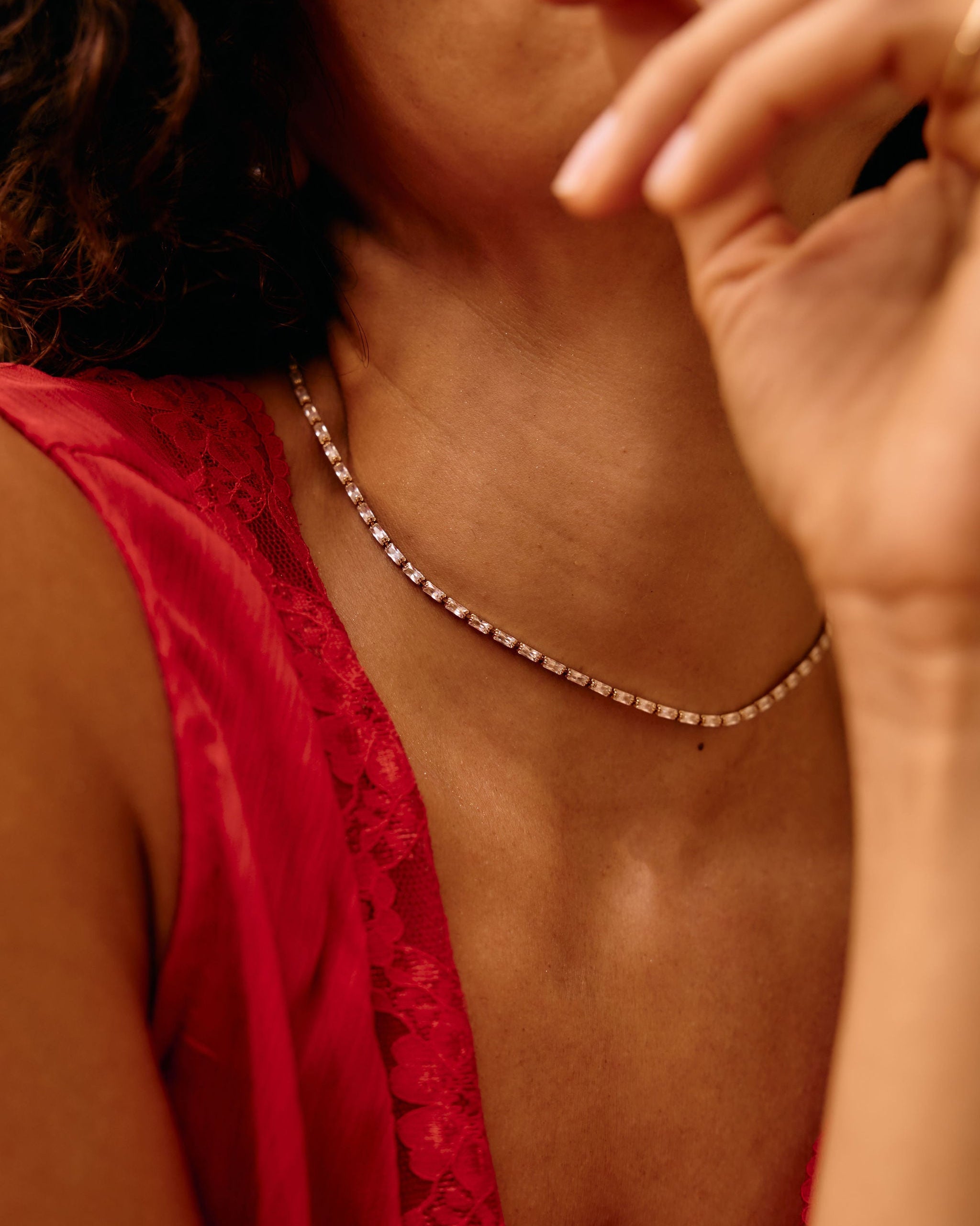 Person wearing a red top and pearl necklace with a blurred background