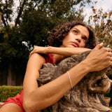 Woman sitting on a stone bench in a park with trees in the background