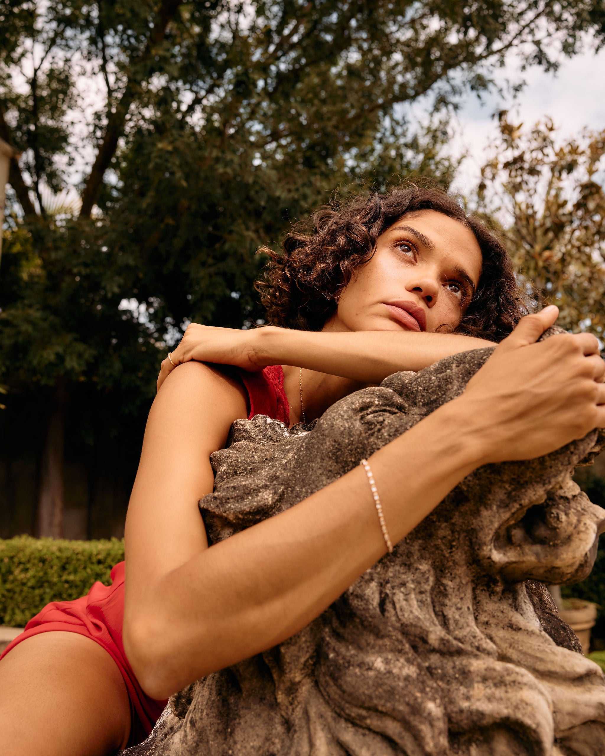 Woman sitting on a stone bench in a park with trees in the background