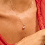 Close-up of a person wearing a delicate necklace with a heart pendant.
