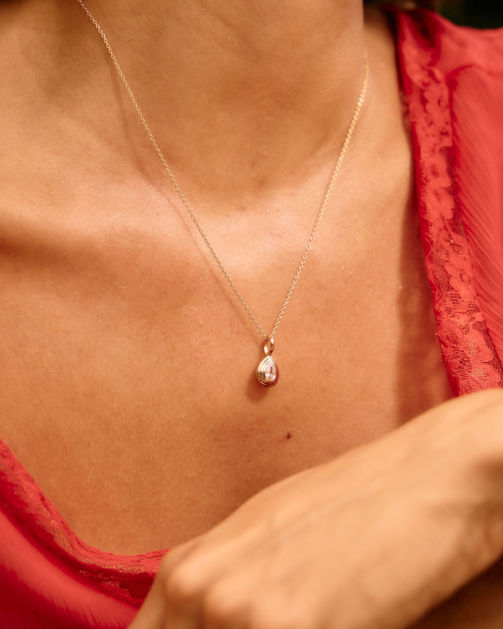Close-up of a person wearing a delicate necklace with a heart pendant.