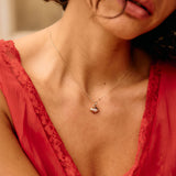 Close-up of a woman wearing a red lace garment and a necklace with a heart pendant.