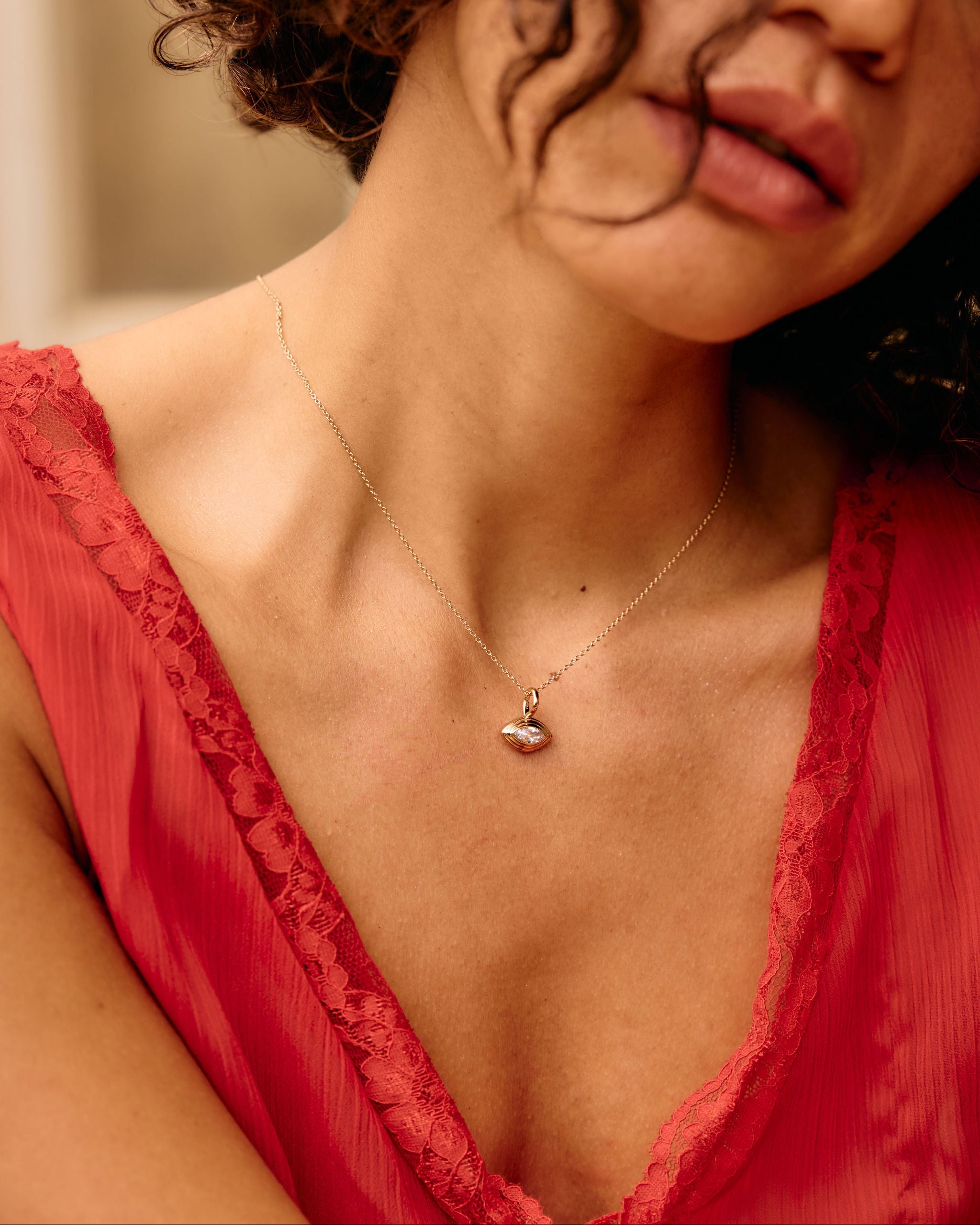 Close-up of a woman wearing a red lace garment and a necklace with a heart pendant.