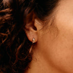 Close-up of an ear with a diamond earring against a blurred background