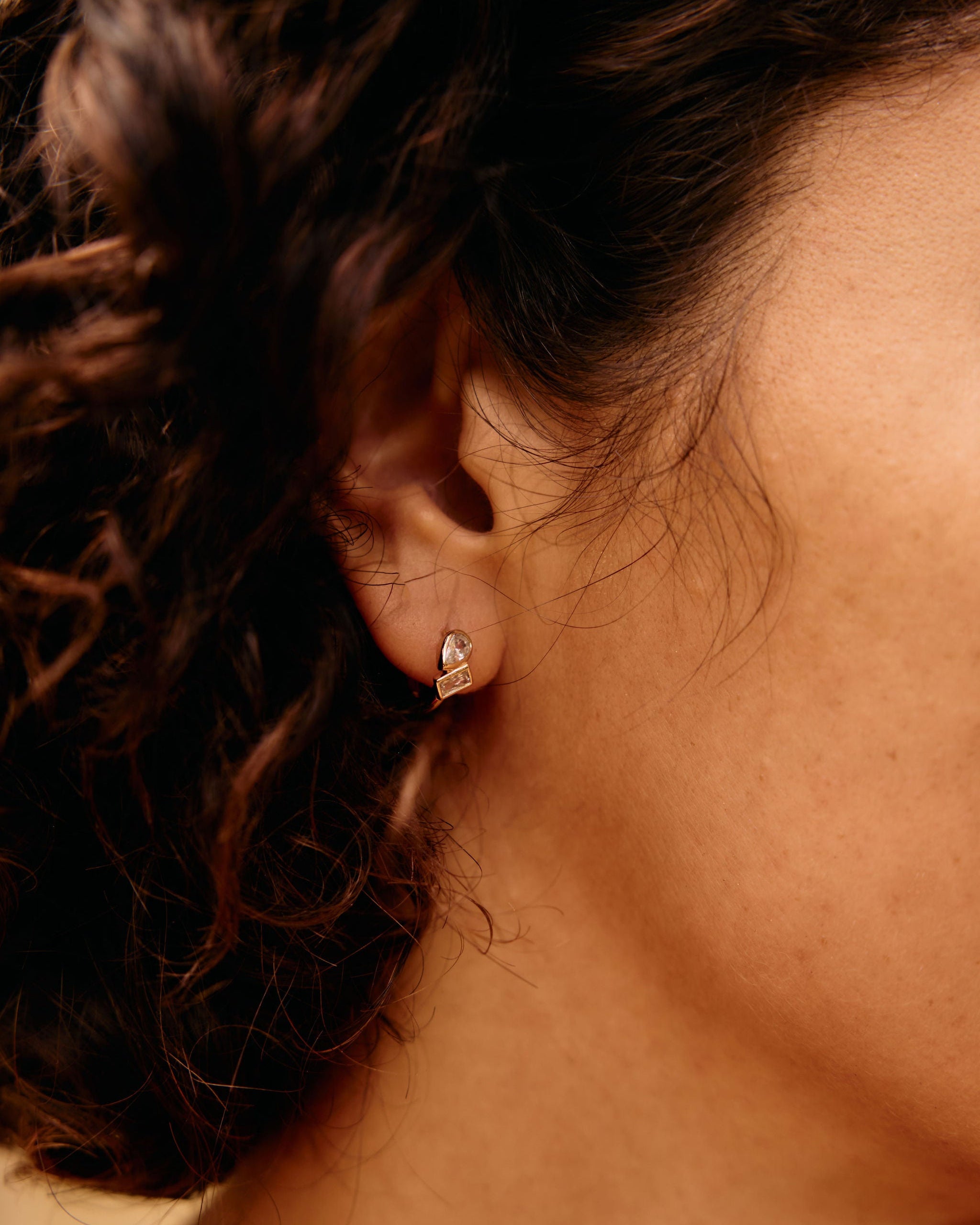 Close-up of an ear with a diamond earring against a blurred background